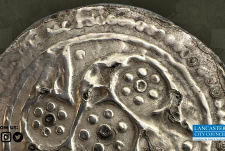 close up photo of ancient silver coin with decorative design of dots and spirals.