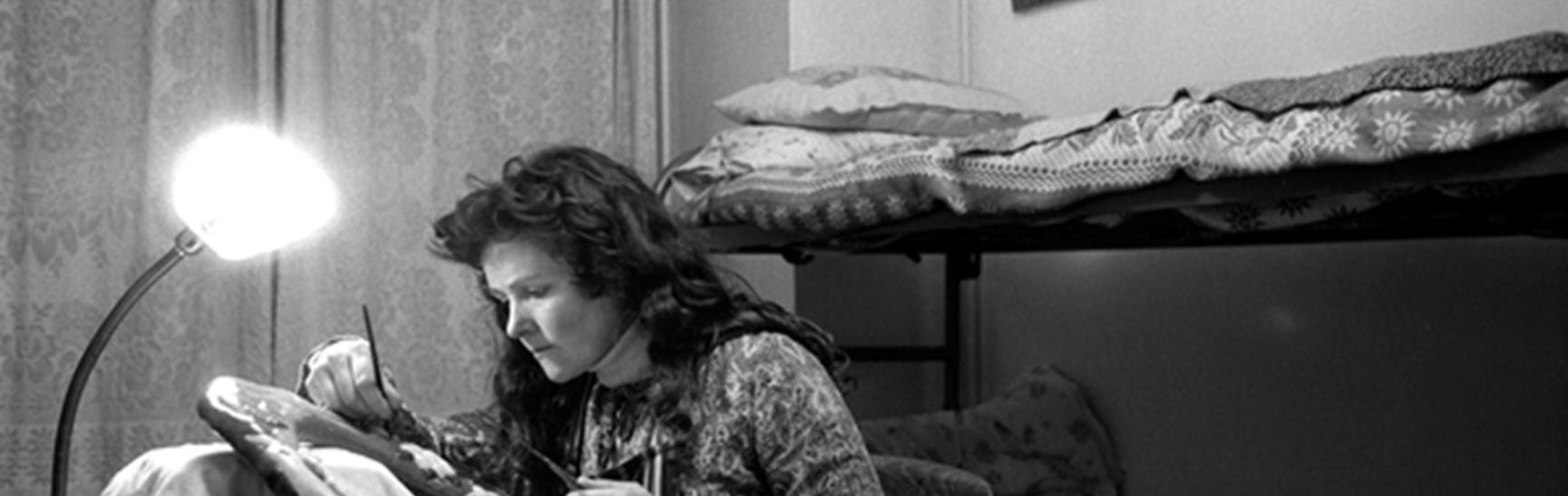 photo of a woman working on a piece of upcycled art based on a toilet seat.