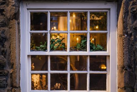 photo of a square window in a stone wall with glimpses of candles inside