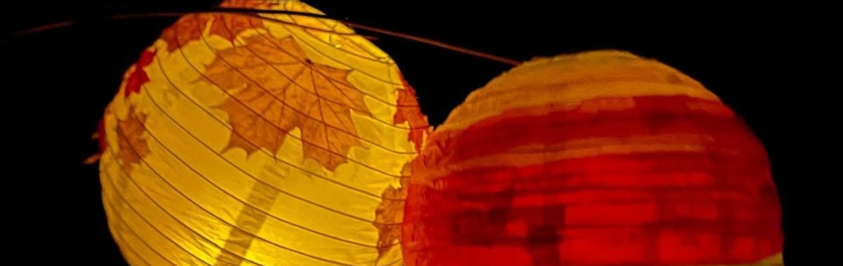 photo of two colourful paper lanterns glowing in the darkness