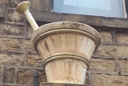 photo of chemist's shop sign in the form of a large model pestle & mortar.
