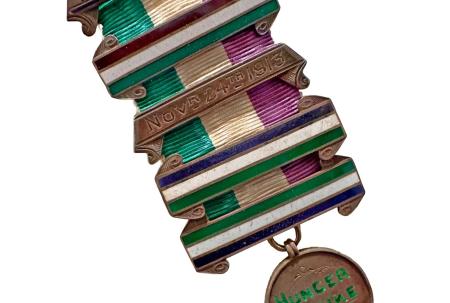 photo of suffragette hunger strike medal on green, white and purple ribbon.